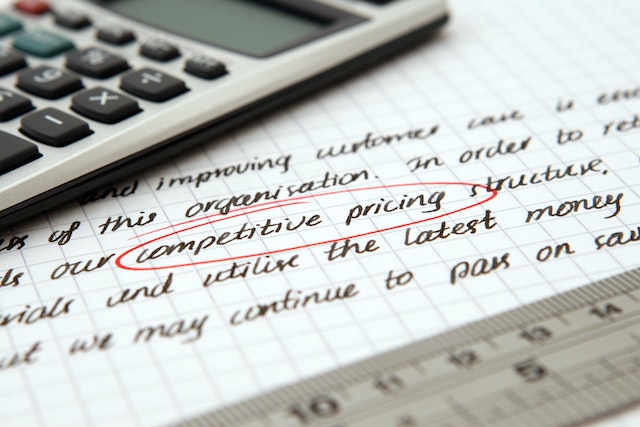 calculator on top of piece of paper with the words competitive pricing circled in red